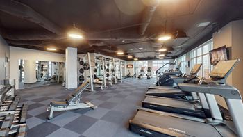 A gym with treadmills and other exercise equipment and windows